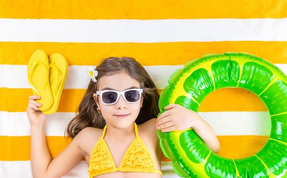 Child girl on a beach towel by the sea. Selective focus. Kid.