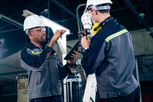 Factory workers working with adept robotic arm in a workshop . Industry robot programming software for automated manufacturing technology .