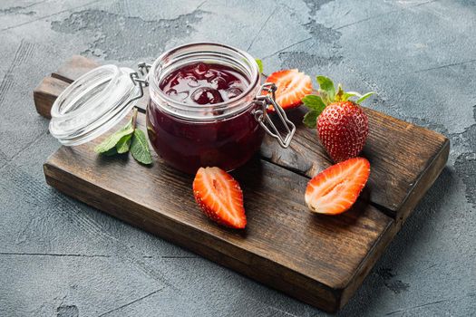 Homemade delicious strawberry jam and with fresh berrie, on gray background