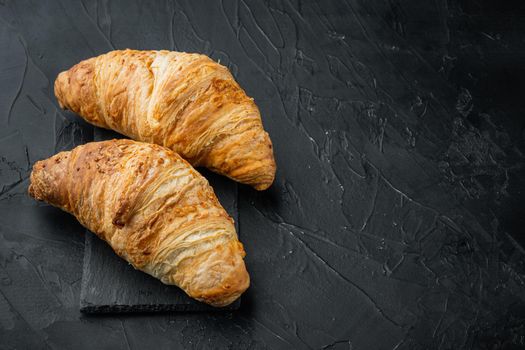 Crispy fresh croissants set, on black stone background, with copy space for text