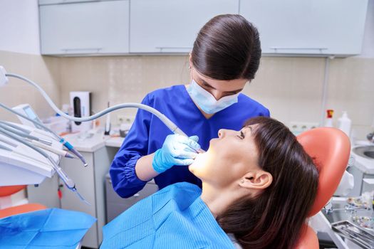 Dental treatment in clinic, woman patient in dental chair, dentist doctor using tools and equipment. Treatment, dentistry, health, teeth care concept