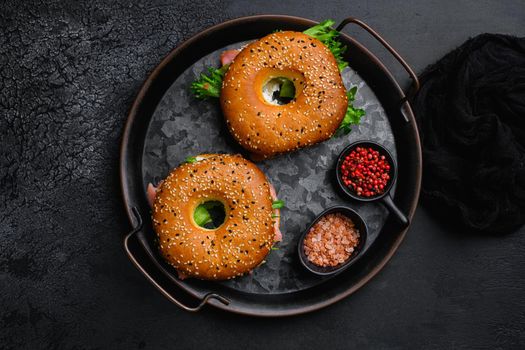 Bagel sandwich with salmon set, on black dark stone table background, top view flat lay