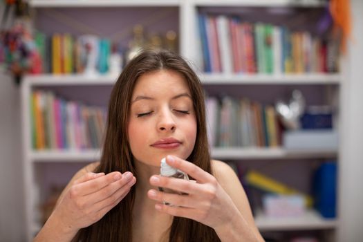 Scent of branded perfume. A young girl is perfuming herself. A brunette girl with her eyes closed imagines the scent of a good perfume.