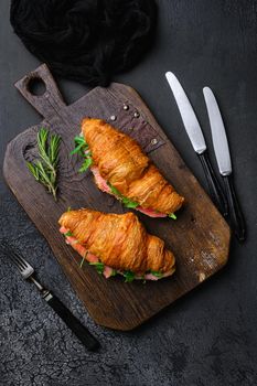 Croissant sandwich with salmon set, on black dark stone table background, top view flat lay