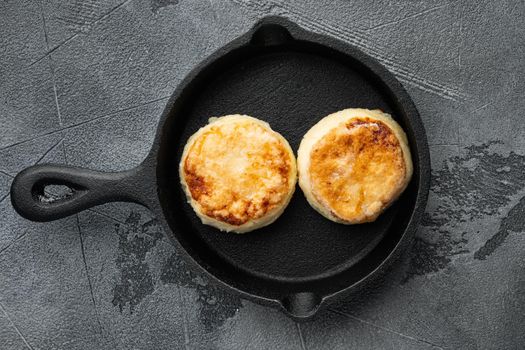 Cottage cheese pancakes, syrniki, ricotta fritters set on cast iron frying pan skillet, top view flat lay, on gray stone table background