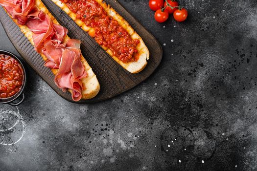 Spanish tomato and jamon toast, traditional breakfast, on black dark stone table background, top view flat lay, with copy space for text