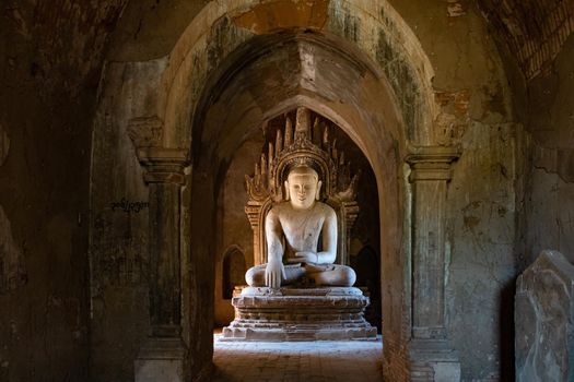 A statue of Buddha stands in the middle of a large stupa in the sacred cultural landscape of Bagan