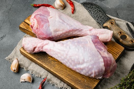 Raw organic turkey legs with ingredients for cooking set, on wooden cutting board, on gray stone table background