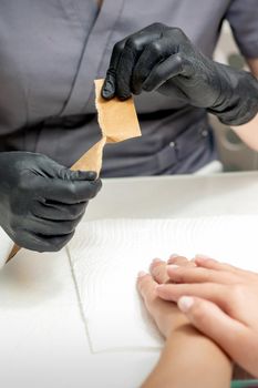 Manicure master opening craft envelope with manicure tools in nail salon