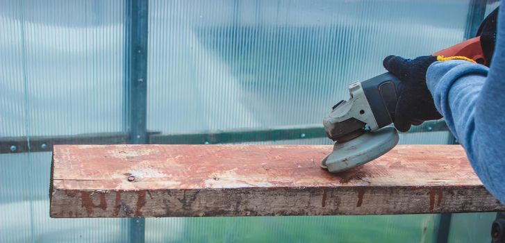 a man is grinding a board. Removing old paint from boards. Carpentry work. selective focus