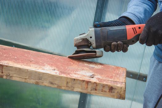 a man is grinding a board. Removing old paint from boards. Carpentry work. selective focus