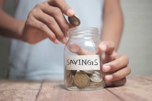 child boy hand hold a saving coins jar .
