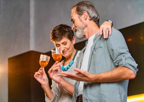 aged couple with glasses of wine in the kitchen