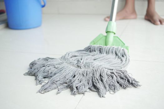 cleaning tiles floor with mop .