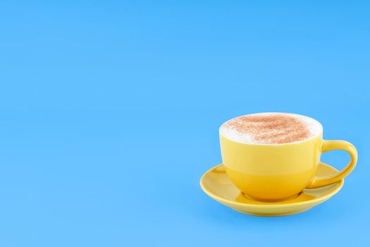 yellow cup of coffee on blue background Space for text