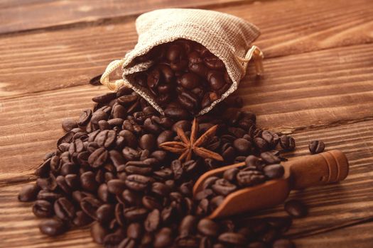 Close up of roasted coffee beans with anise in sackcloth bag on a wooden background Coffee is always a good idea