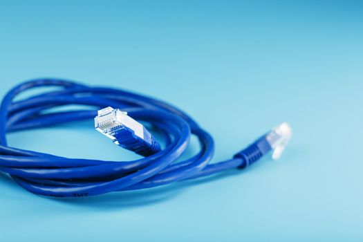 Blue Ethernet Cable Connectors Patch cord cord close-up isolated on a blue background with free space