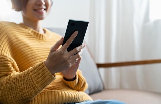 Close up image of a beautiful asian woman using mobile phone with feeling happy at home.