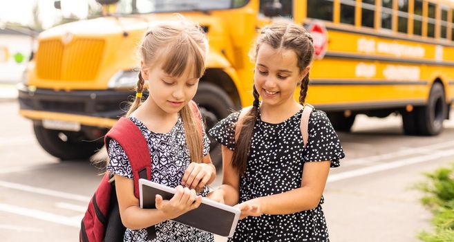 Portrait of two girls with school bags after lesson in school.