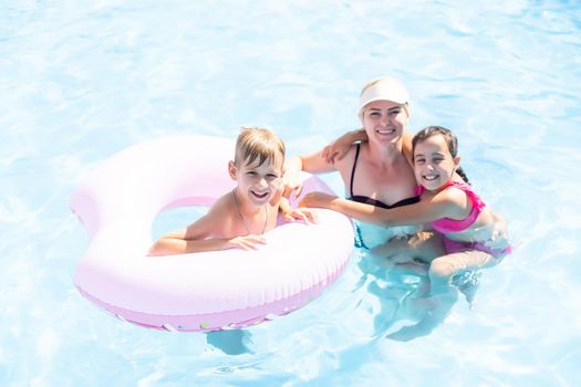 Mother with children in swimming pool at water park.