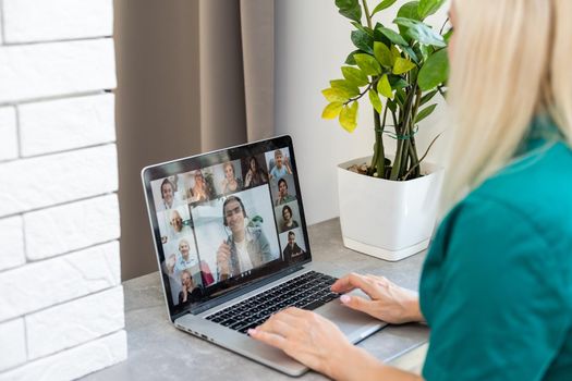 Cropped image of young woman using laptop for video conference at home.