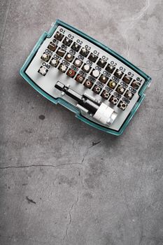 A set of metal power bits in a box on a gray background, for repair and maintenance