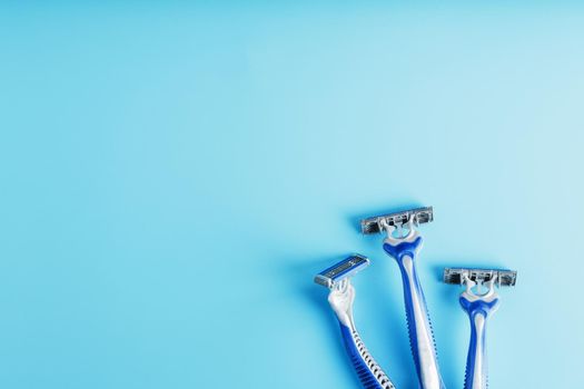 Three shaving machines on a blue background with free space, top view