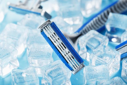 Shaving machine on a blue background with ice cubes. The concept of cleanliness and frosty freshness