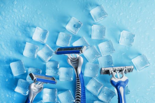 Blue shaving machines in a row on a blue background with ice cubes. The concept of cleanliness and frosty freshness