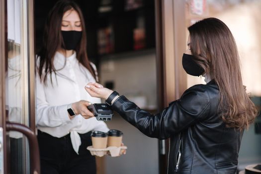 Female customer making wireless or contactless payment using smartwatch. Cashier accepting payment over nfc technology.