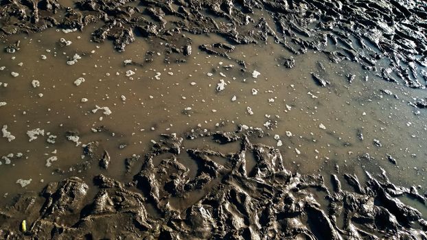 Footprint or imprint shoe in the mud.Mud texture or wet brown soil as natural organic clay and geological sediment mixture as in roughing it in a dirty muddy country ground after the rain or rainy