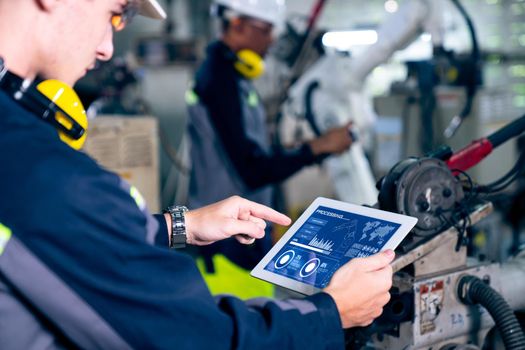 Factory workers working with adept robotic arm in a workshop . Industry robot programming software for automated manufacturing technology .