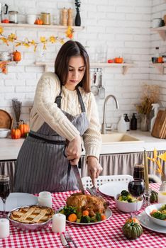 Happy Thanksgiving Day. Autumn feast. Woman celebrating holiday cooking traditional dinner at kitchen with turkey, vegetables and pumpkin pie