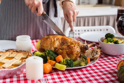 Happy Thanksgiving Day. Autumn feast. Woman celebrating holiday cooking traditional dinner at kitchen with turkey, vegetables and pumpkin pie, cutting