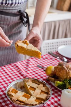 Happy Thanksgiving Day. Autumn feast. Woman celebrating holiday cooking traditional dinner at kitchen with turkey, vegetables and pumpkin pie, cutting pie