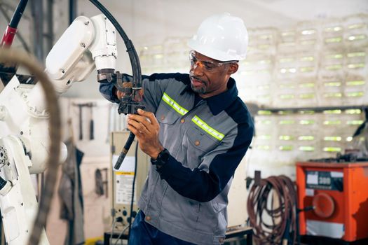 African American factory worker working with adept robotic arm in a workshop . Industry robot programming software for automated manufacturing technology .