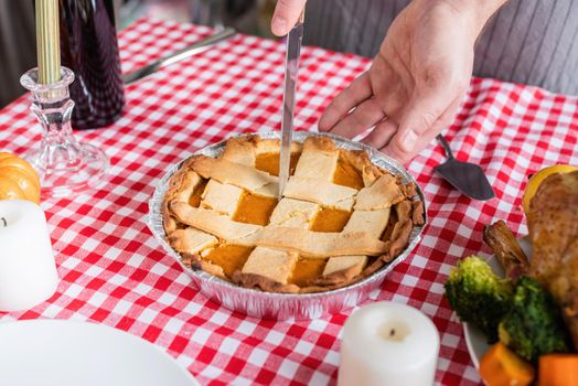 Happy Thanksgiving Day. Autumn feast. Woman celebrating holiday cooking traditional dinner at kitchen with turkey, vegetables and pumpkin pie, cutting pie