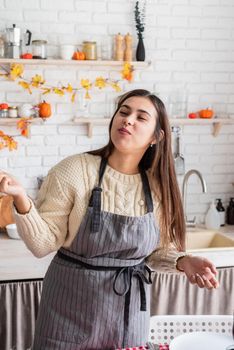 Happy Thanksgiving Day. Autumn feast. Woman celebrating holiday cooking traditional dinner at kitchen with turkey, vegetables and pumpkin pie, cutting pie