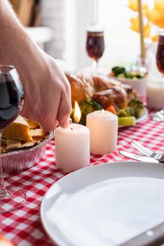 Happy Thanksgiving Day. Autumn feast. man celebrating holiday cooking traditional dinner at kitchen with turkey, vegetables and pumpkin pie, lighting candles