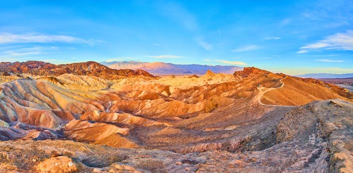 Image of Mountains featuring waves of sediment colors and hiking path through the peaks in Death Valley