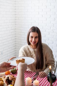 Happy Thanksgiving Day. Autumn feast. Woman and man celebrating holiday eating traditional dinner at kitchen with turkey, vegetables and pumpkin pie