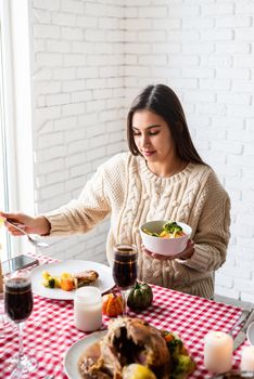 Happy Thanksgiving Day. Autumn feast. Woman celebrating holiday eating traditional dinner at kitchen with turkey, vegetables and pumpkin pie