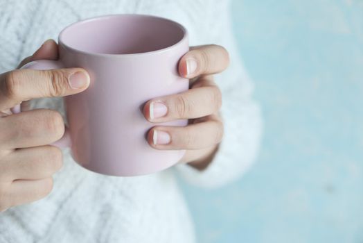 Close up of women's hand holding white color coffee cup..