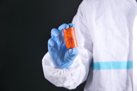 doctor hand in protective glass holding pill container.