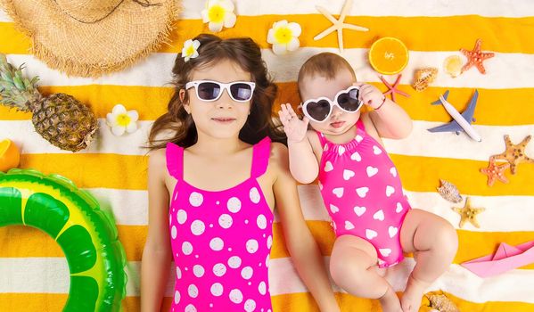 Baby sisters on a beach towel at the sea. Selective focus. Child.