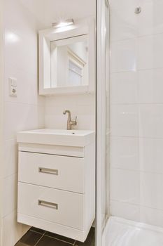 Sink and mirror, next to the shower stall in a modern bathroom with white tiled walls