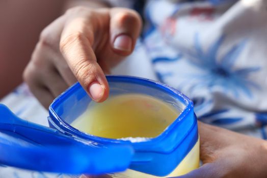 woman using petroleum jelly onto skin at home close up..