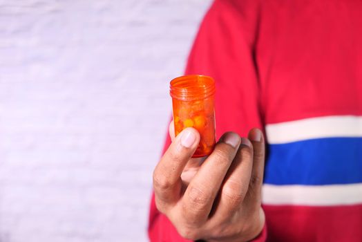 Close up of person hand holding pill container .