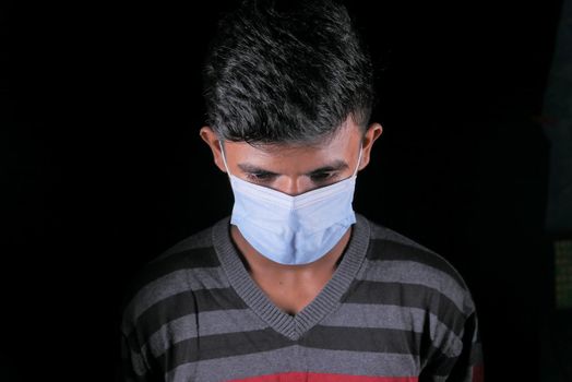 A young man with protective mask isolated on black .