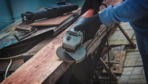 a man is grinding a board. Removing old paint from boards. Carpentry work. selective focus